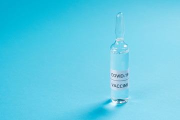 Vaccine for COVID-19. An ampoule with a medicine for coronavirus on a blue background. Copyspace....