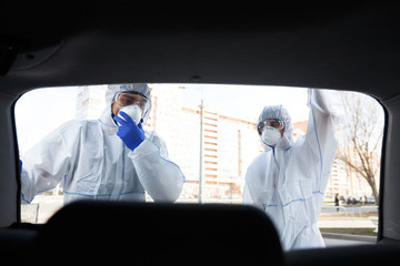 Medical worker in virus protective suit open trunk and looking