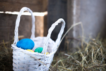 Easter eggs in a basket on a hay with a blurred background