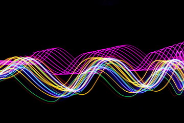 Pink and multi color light painting photography, long exposure photo of gold, pink, green and blue waves of vibrant color against a black background