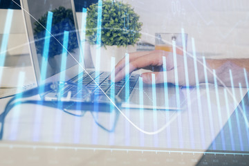 Multi exposure of graph with man typing on computer in office on background. Concept of hard work. Closeup.