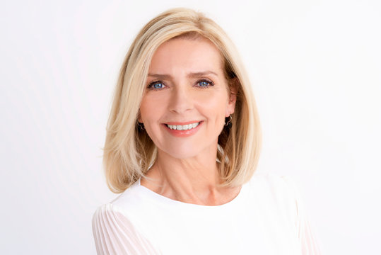 Headshot of blond senior woman while standing at isolated white background