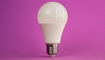 white light bulb on a purple background standing exactly up