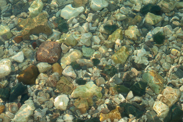 Sea stones and sun glare. Marine background and wallpaper. Pebbles underwater.  Ocean stones.
