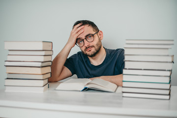 Young white European brunette man nerd in glasses teaches lessons, reads books, studied at...
