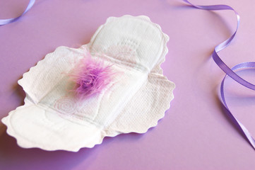 Menstrual pads with a fluff on a lilac background.