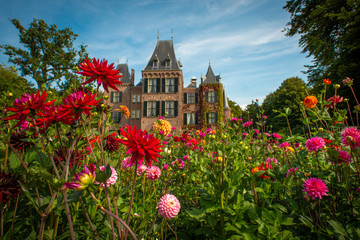 Garden with flowering dahlias in shades of orange and red in front of Keukenhof castle on a sunny...