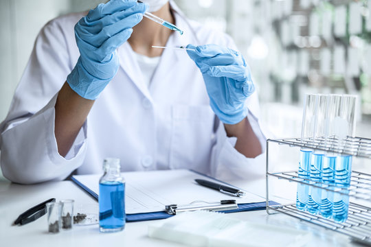 Scientist or medical in lab coat holding test tube with reagent, mixing reagents in glass flask, glassware containing chemical liquid, laboratory research and testing of Microscope