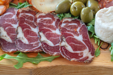 Sliced meat appetizer, meat dessert before lunch. Hamon sausages smoked products ham cheese and olives. Mediterranean food.