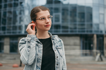 young girl in stylish gold goggles in black t-shirt and denim jacket on the background of a modern glass building outdoor. Training, Institute.