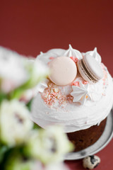 Easter cake kulich. selective focus. Traditional easter sweet bread decorated with meringues and macaroons on a stand with a hare on a brown background. Copy space