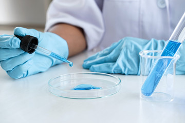 Fototapeta premium Biochemistry laboratory research, Scientist or medical in lab coat holding test tube with using reagent with drop of color liquid over glass equipment working at the laboratory