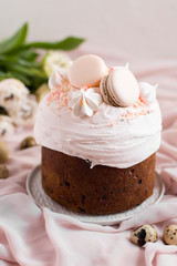 Easter cake kulich. selective focus Traditional easter sweet bread decorated with meringues and macaroons on a plate on a background of a vase with white tulips. Copy space