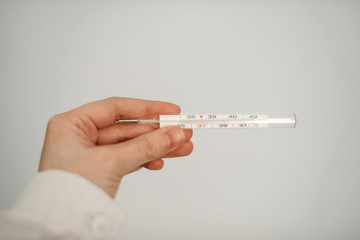 Thermometer in doctor's hand in white coat.