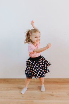 Portrait of caucasian girl kid dancing at home looking to the camera