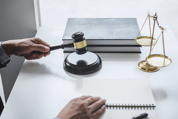 Male lawyer or judge working with contract papers, Law books and wooden gavel on table in...