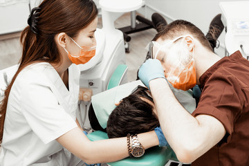 A young male dentist doctor treats a patient. Medical manipulations in dentistry, surgery....
