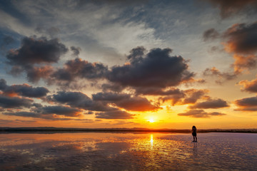 Fototapeta premium Person takes a photo of beautiful sunset landscape with a lake, dramatic golden sky above reflects in the water.