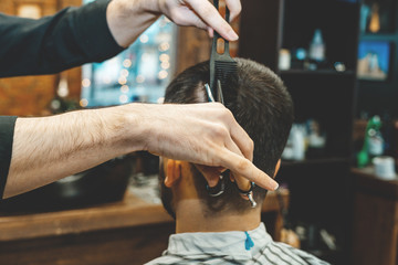 Haircut at the hairdresser. Barber cuts the hair on the client's head. The process of creating hairstyles for men. A man in a barbershop. The near plan. Equipment stylist. Selective focus