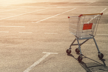 Single abandoned empty shopping trolley in an empty parking lot near a supermarket in the absence...