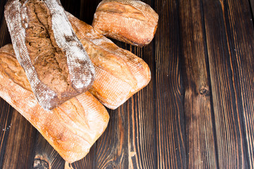 A variety fresh homemade loaves of ciabatta on a dark wooden background.
