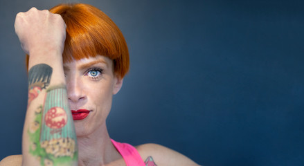 Ritratto di bellissima ragazza tatuata con i capelli rossi a caschetto e gli occhi chiari, vestita...