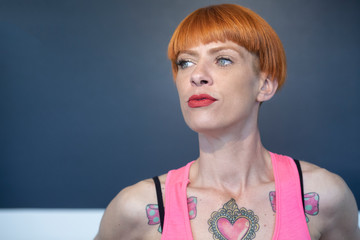 Ritratto di Ragazza con i tatuaggi, capelli rossi a caschetto e gli occhi chiari,  vestita con una...