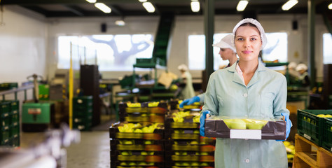 Young woman in uniform during sorting at warehouse at apples factory
