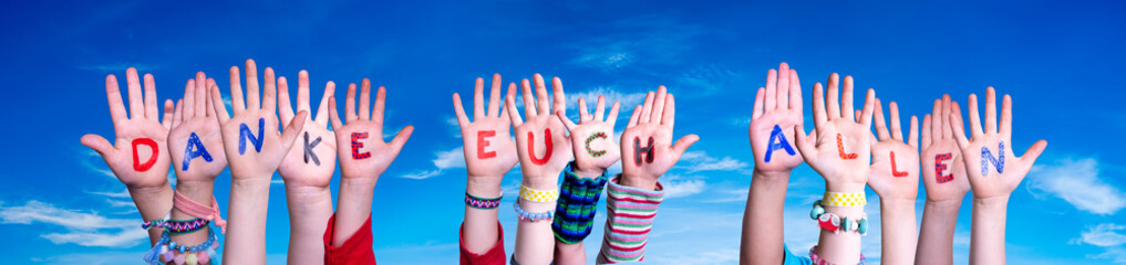 Kids Hands Holding Colorful German Word Danke Euch Allen Means Thank You All. Blue Sky As Background
