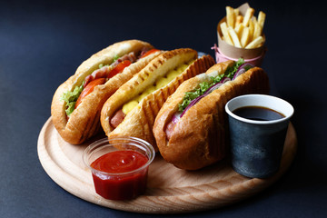 Three hot dogs, ketchup, coffee, French fries lying on the wooden plate.  Mock up.