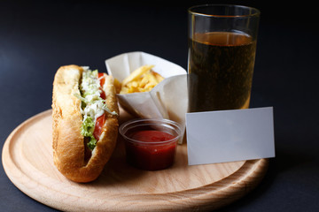 Hot Dogs with French fries and ketchup on wooden plate.