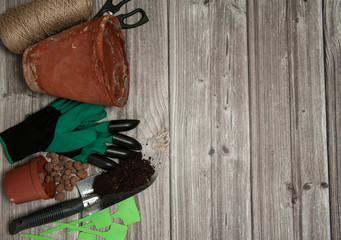 Free time. Spring transplanting of domestic plants. The border is made of pots with drainage, a scoop of earth, scissors, string for tying and gardening gloves on a wooden background. Free space.