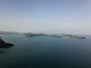 Tropical island, shoot from sky on sunset time, mountain, small free beach, behind Phuket city and mountains. Travel tropical concept