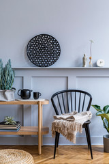 Stylish scandinavian living room interior with design black chair, wooden console, plants, books, decoration, tea pot, rattan pouf and elegant accessories in modern home decor.