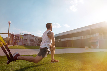 Fototapeta premium Home workout routine. One man doing suspension straps exercises open air.