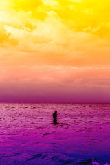 Abstract colorful cloudy sky and man walkingn into the sea