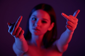 Young rude female showing indicent gesture with her hands in front of camera