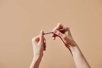 Foto op Aluminium Manicure Bijgesneden beeld van vrouw die manicure doet met behulp van cuticula pusher geïsoleerd op beige