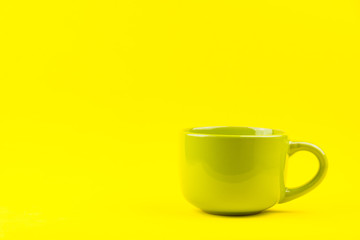 Green cup isolated on yellow background.