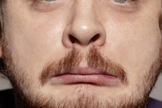 Sad, upset. Close up of face of beautiful caucasian young man with redhair beard, focus on mouth. Human emotions, facial expression, cosmetology, body and skin care concept. Well kept skin. Wellbeing.