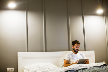 Young man reading book in the bed