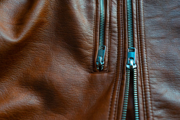 Brown textured leather jacket zippers. Background of brown leather jacket. Top view shiny detail...