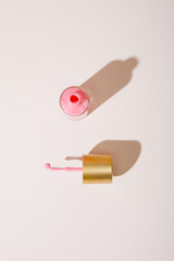 Top view of opened bottle of pink nail polish on white background