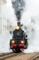 Fototapeta na wymiar Black retro steam train. Old locomotive in motion. Railroad travel, railway tourism. Transportation. Railway oldtimer.