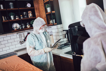 Specialists in protective suits take samples from surfaces in the home to test for a new corona...