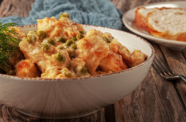 Braised chicken fillet with green peas on a wooden table