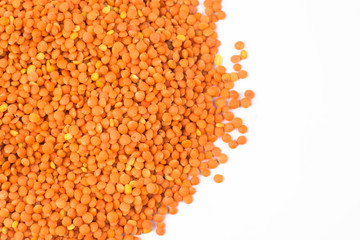 Orange color lentil seeds stacked together in a heap before a white background