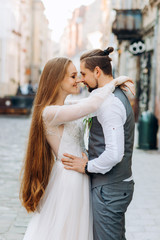 Newlyweds walking in the wedding day. Sweet couple hugging each others on street background