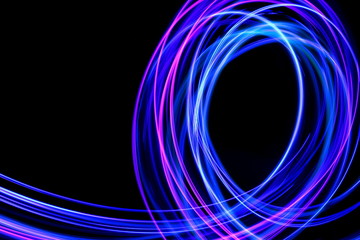 Light painting photography, long exposure photo of purple and blue streaks of vibrant color against a black background