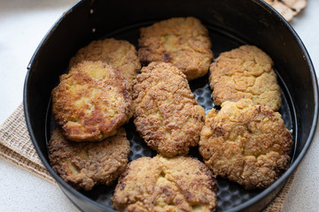 fried cutlet in a black pan, rustic food. close-up